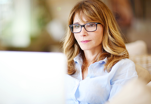 Frau Beamtin mit Brille sitzt vor dem Laptop